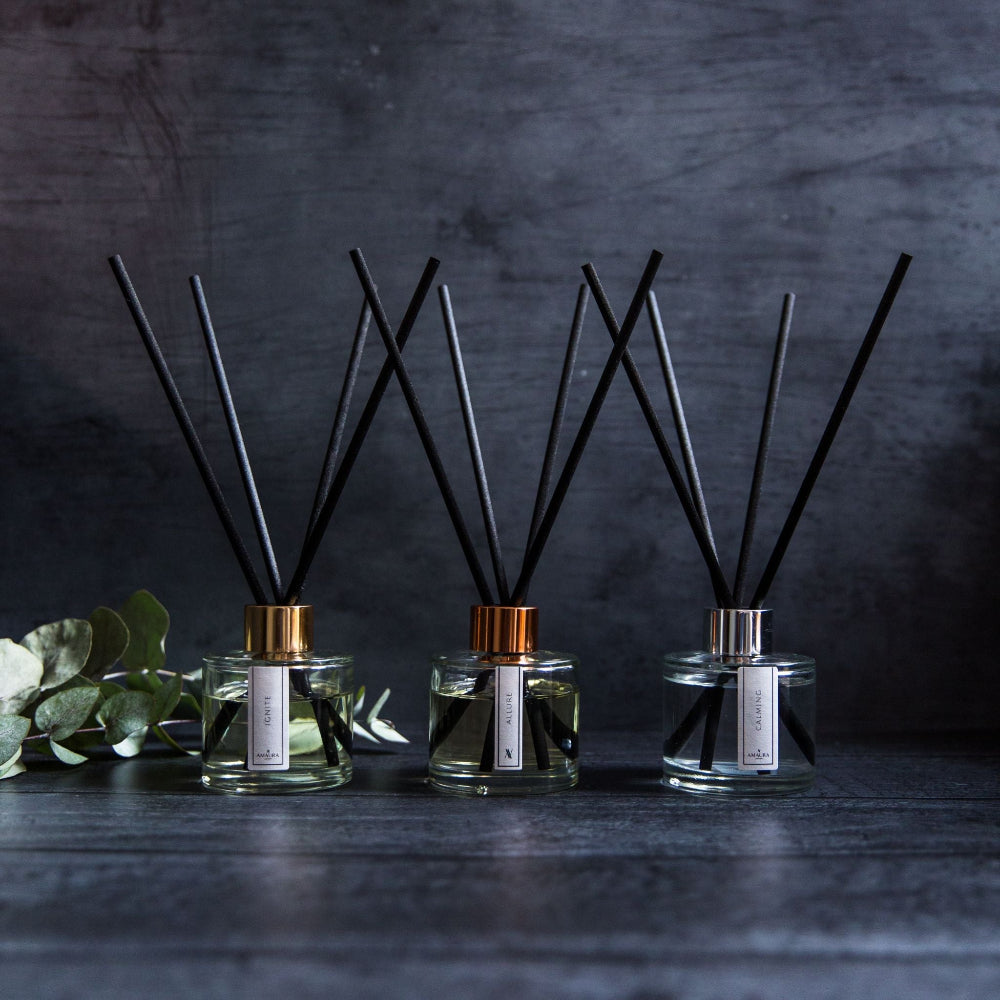 Three diffusers with black sticks on a dark background