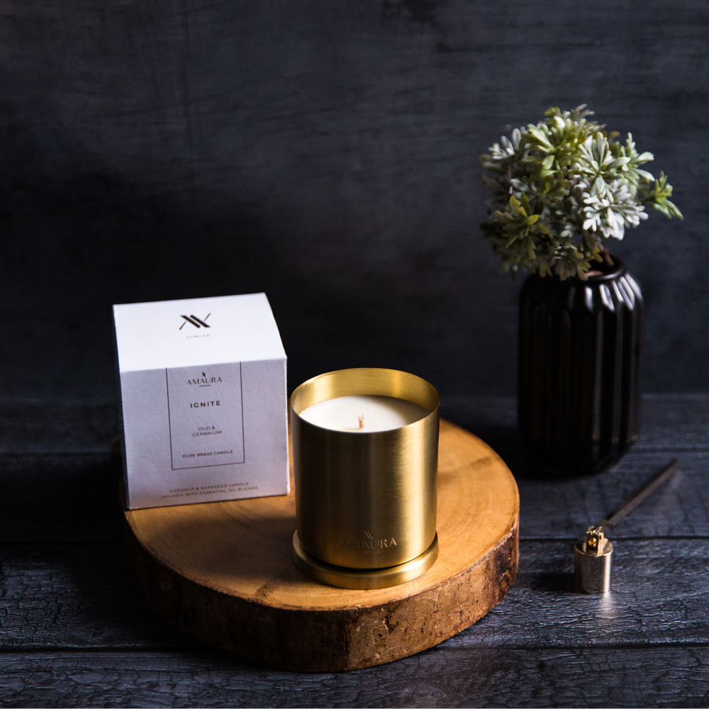 Gold candle on a wooden stand with a box and plant in the background