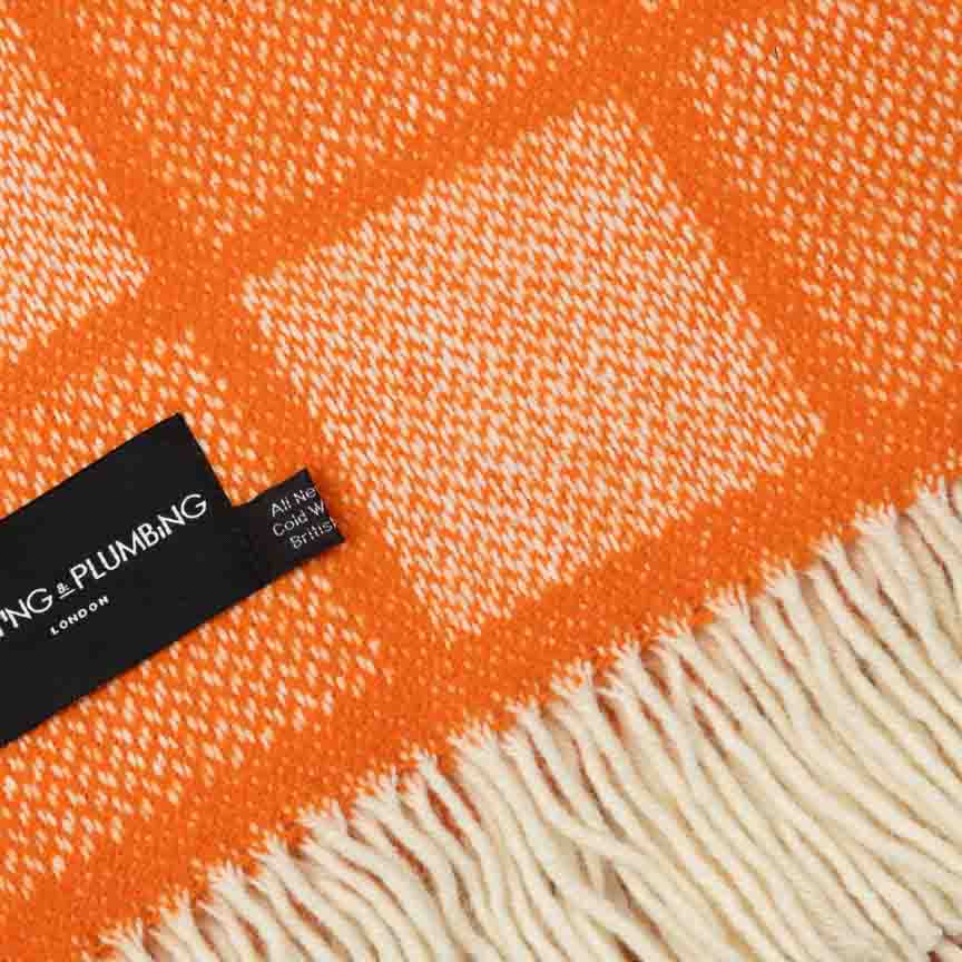 Orange fabric with a white pattern and a visible brand label on a textured background