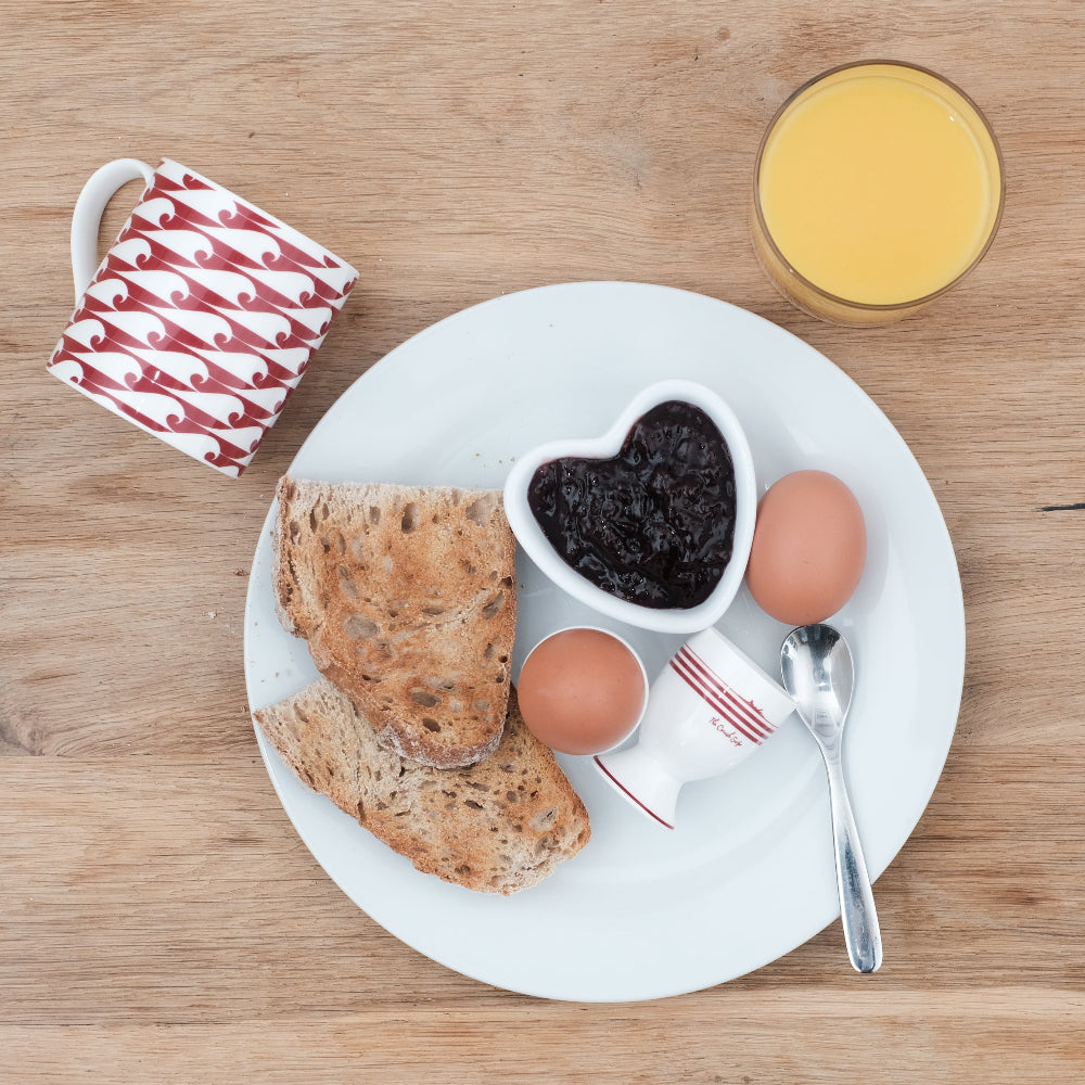Breakfast setting with toast, eggs, jam, and juice on a wooden table.