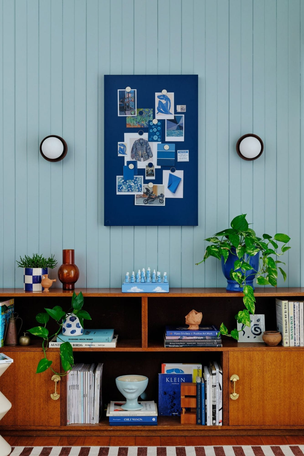 Nest living room with a blue wall, wooden shelf, and decorative items.