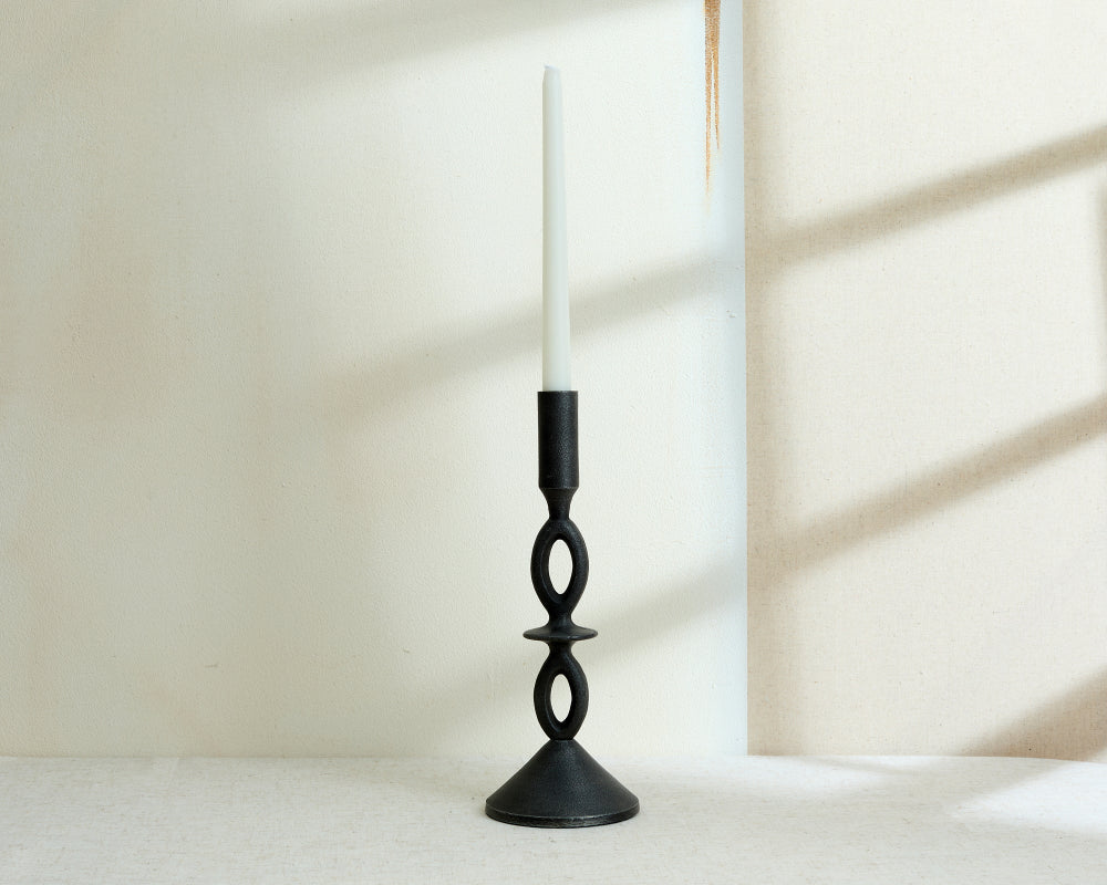 Black candle holder with a white candle on a light background