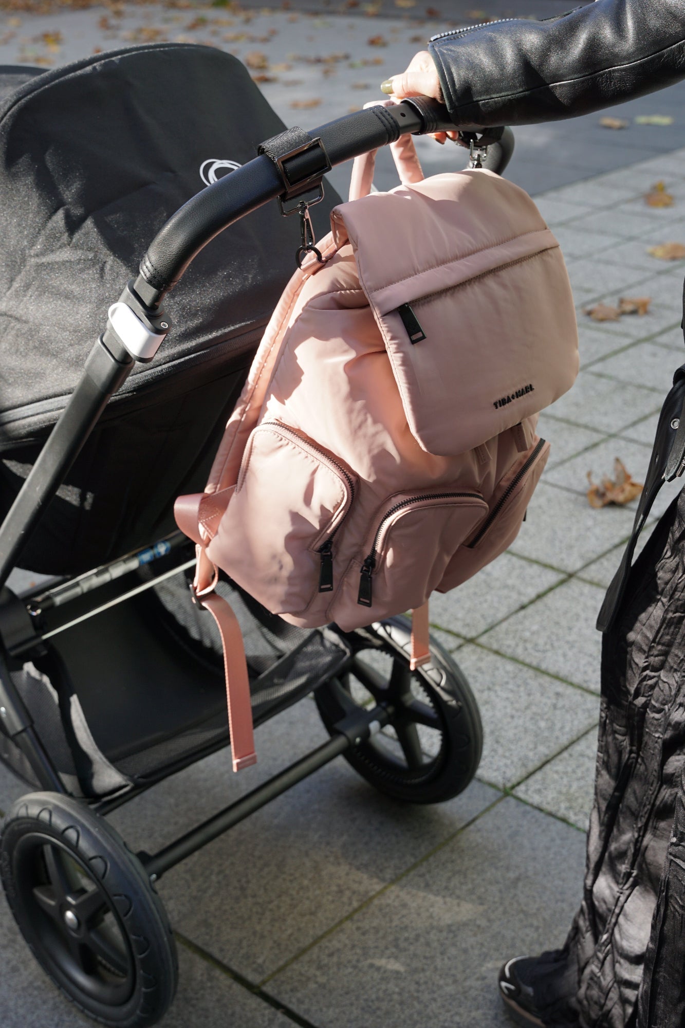 Pink backpack attached to a stroller on a sidewalk