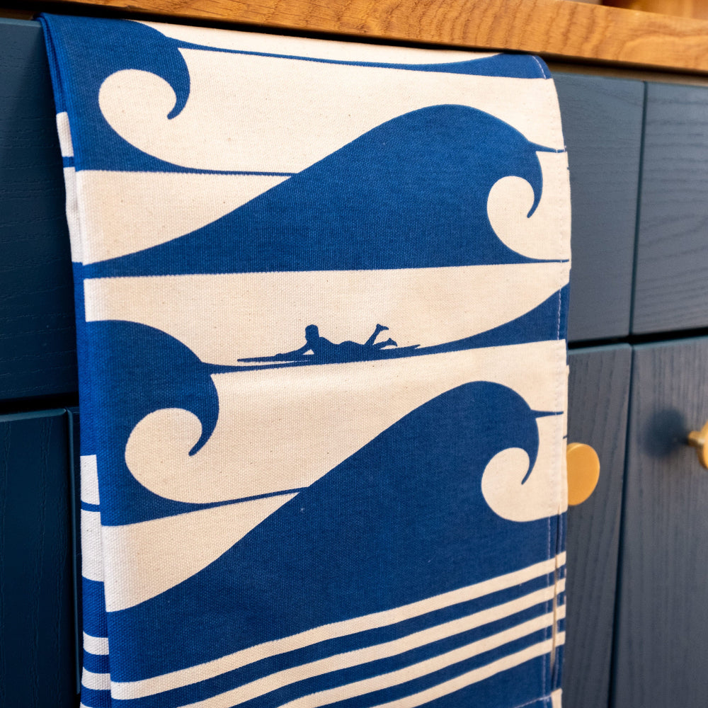 Towel with wave and surfer design hanging on a wooden draw in a kitchen