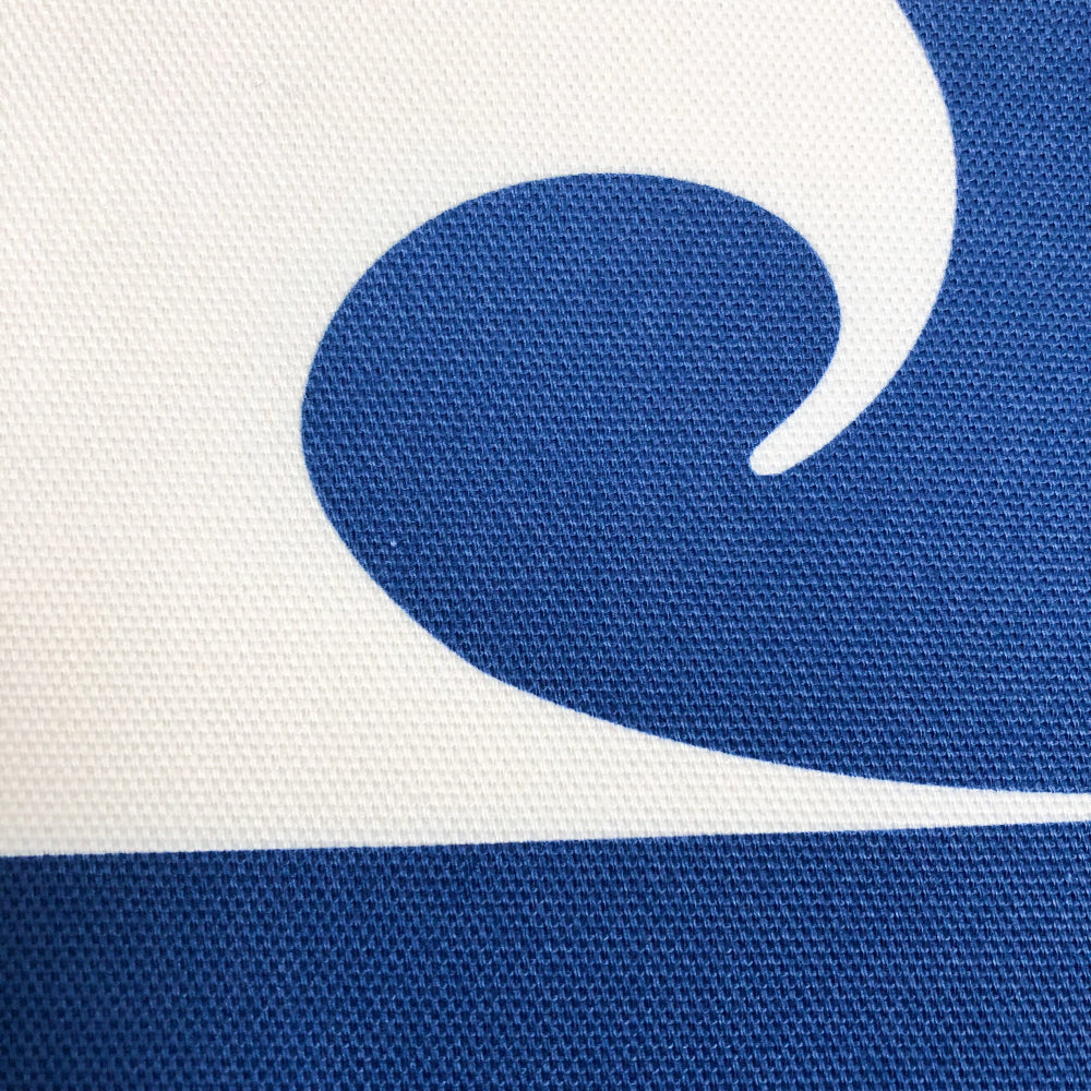 Close-up of a blue and white wave design on a textured surface cushion cover