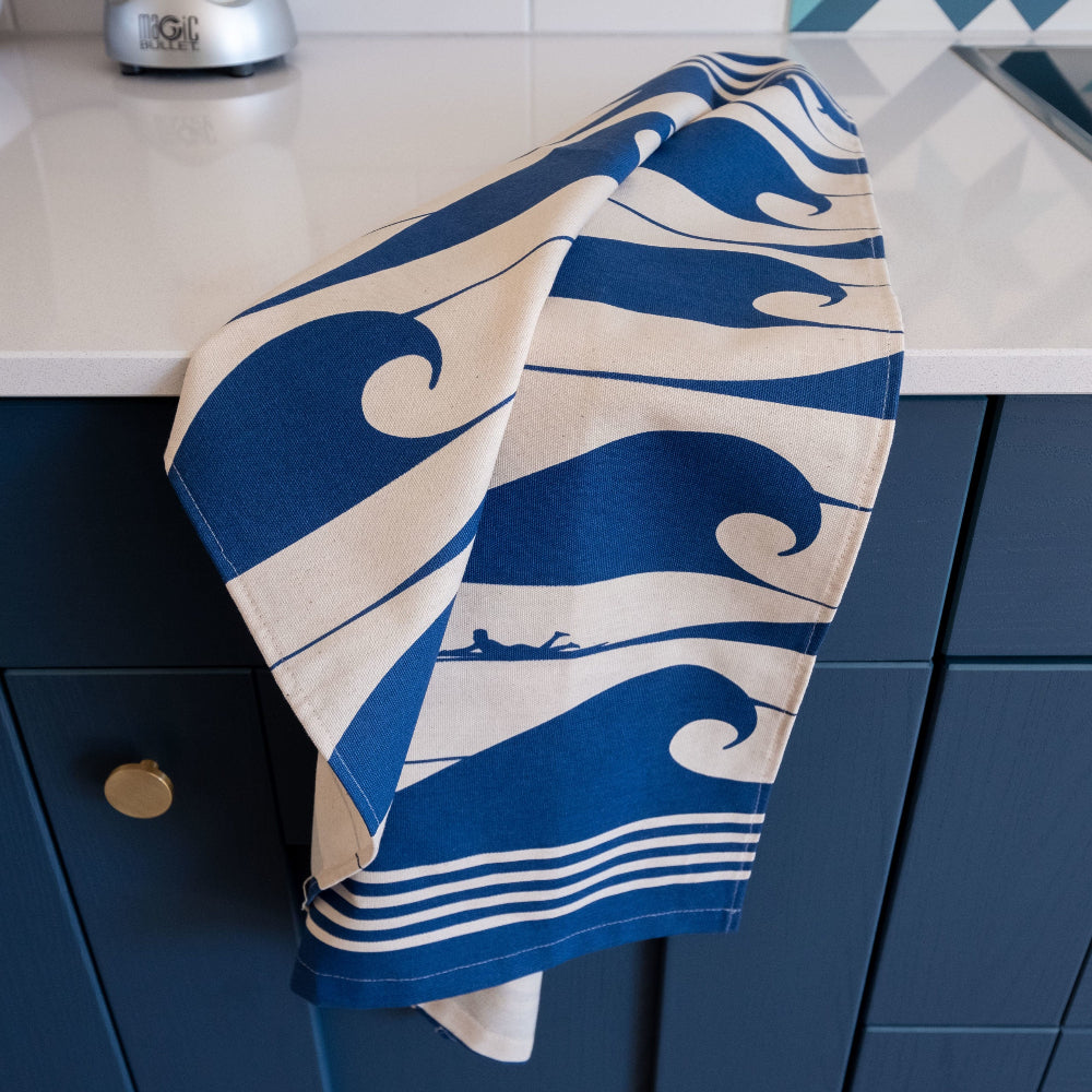 Blue and white wave-patterned towel draped over a blue cabinet in kitchen.