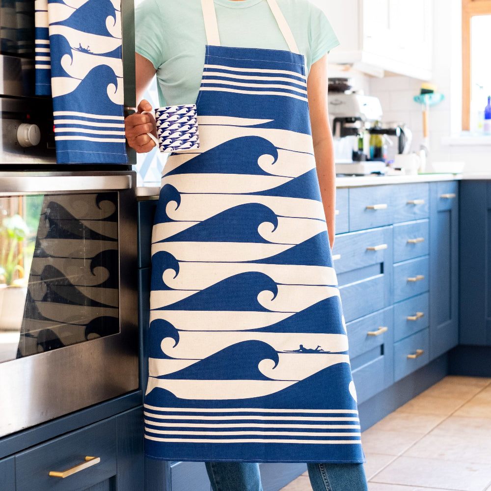 Person wearing a blue and white wave-patterned apron in a kitchen.