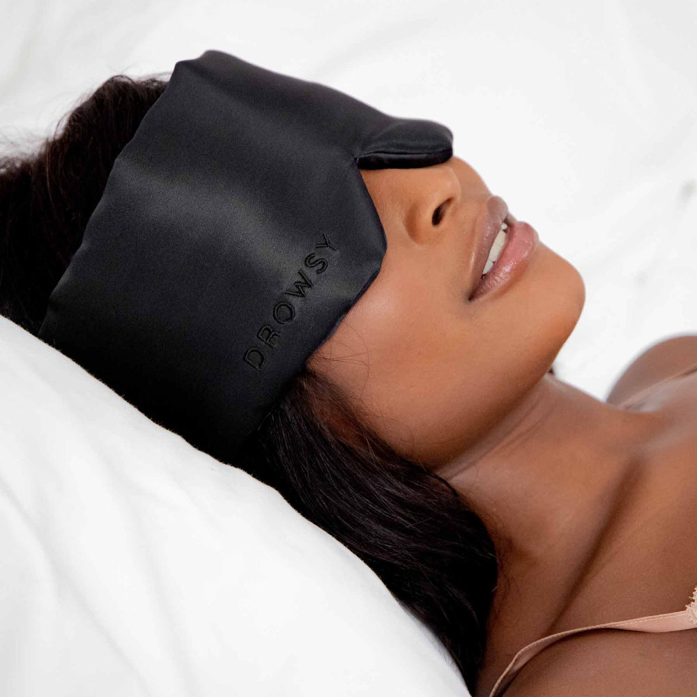 Person wearing a black sleep mask while lying down.