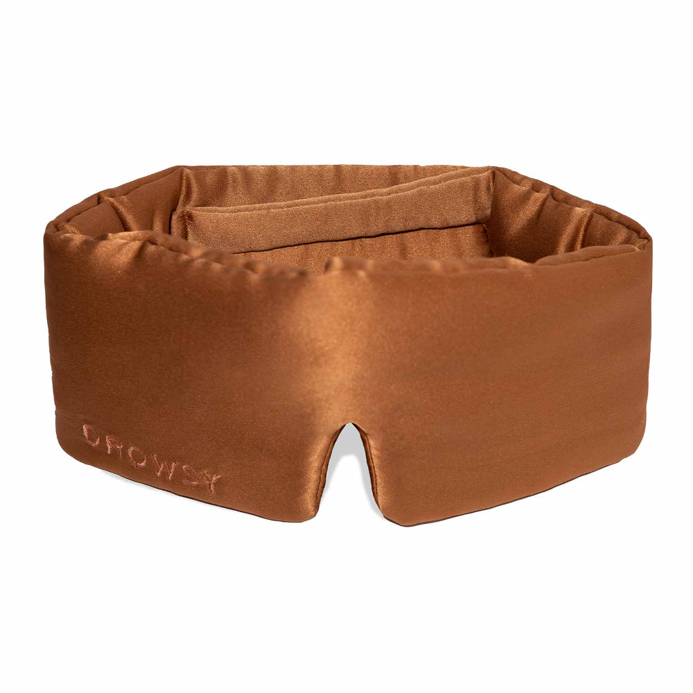 A pumpkin orange silk sleep mask with a plush design and the brand 'DROWSY' visible on the material.
