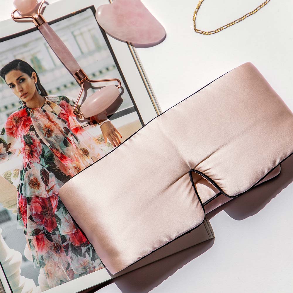 Silk pink sleep masks flatlay with magazine, face roller, jewellwery and quartz face tools