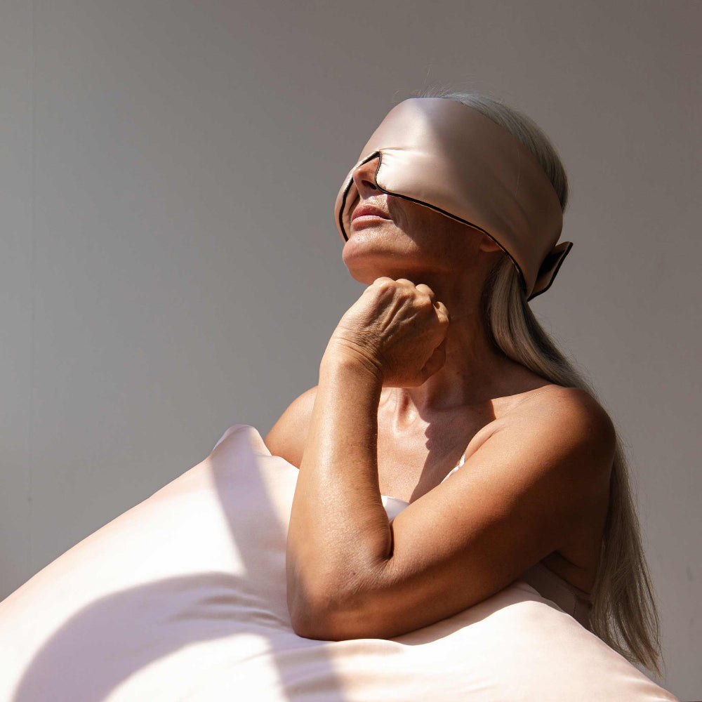 Person wearing a beige sleep mask in a sunlit room.