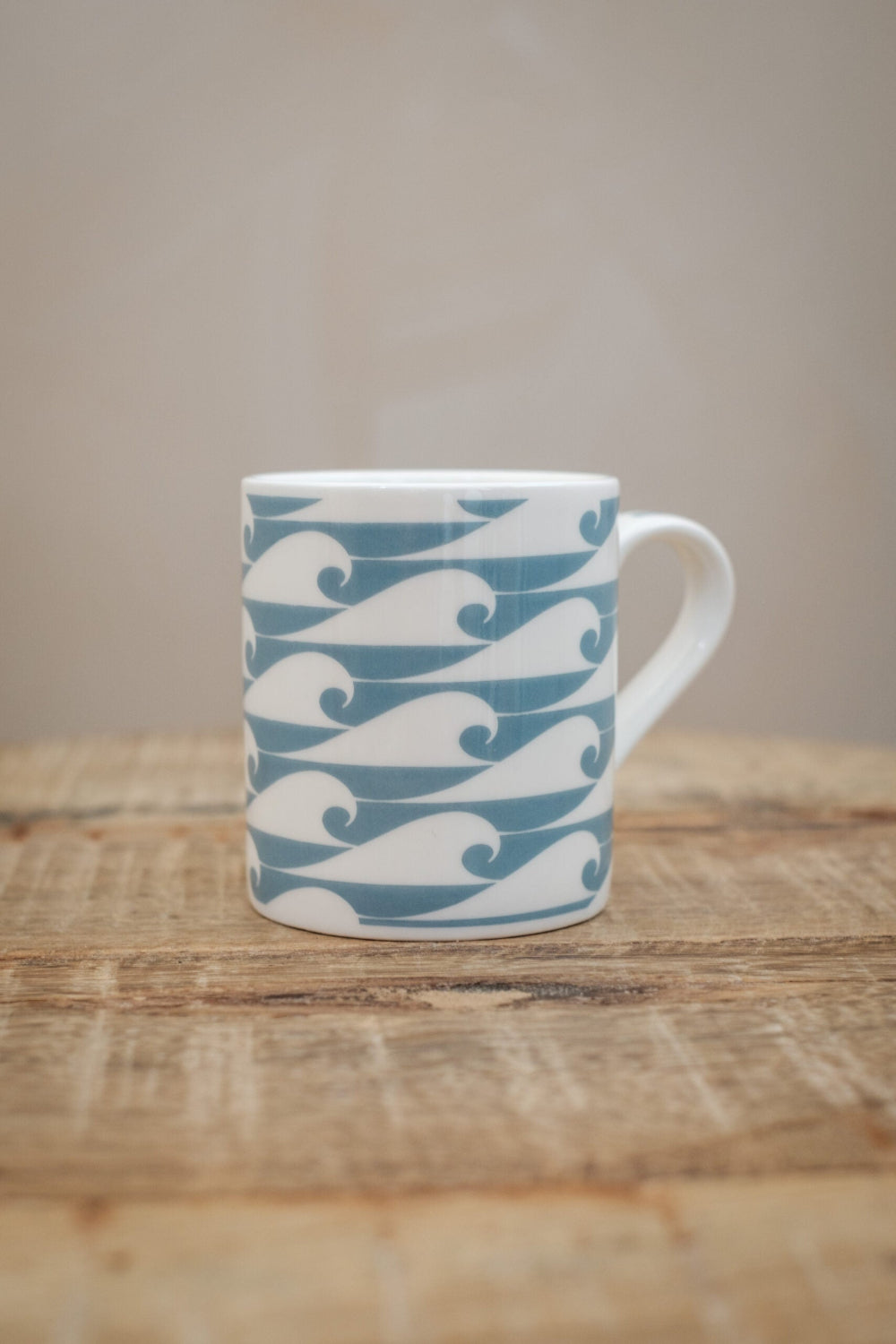 White Espresso mug with blue wave pattern on a wooden surface