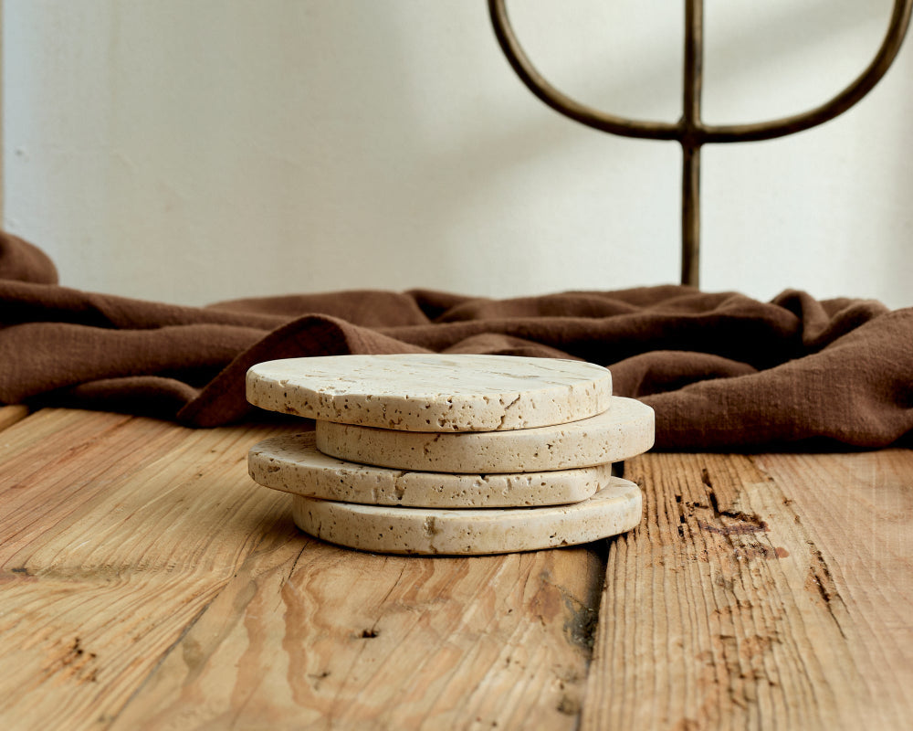 Stack of Travertine coasters on a wooden surface with a brown fabric background