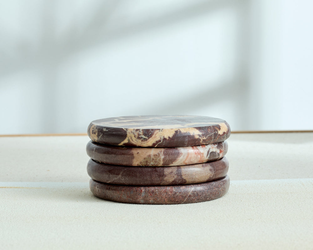 Stack of marbled stone coasters on a light surface with a blurred background