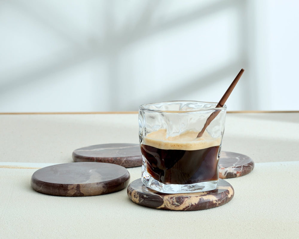 Glass of iced coffee with a wooden spoon on a marble coaster
