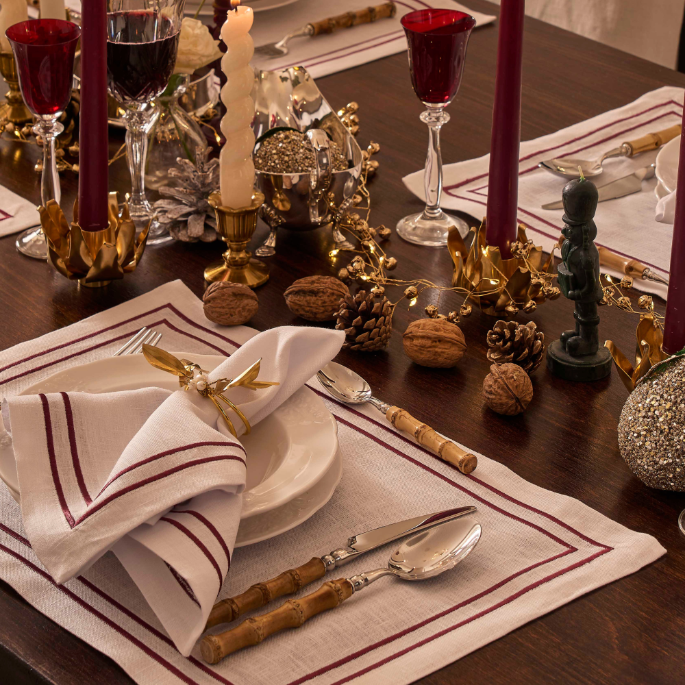 Decorative table setting with red and gold accents, including cutlery and candles.