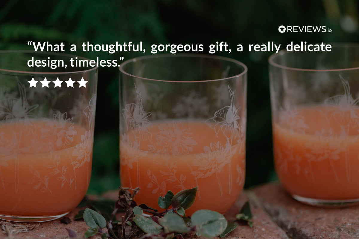 Three glasses of orange juice with decorative patterns on a blurred natural background, featuring a customer review quote.