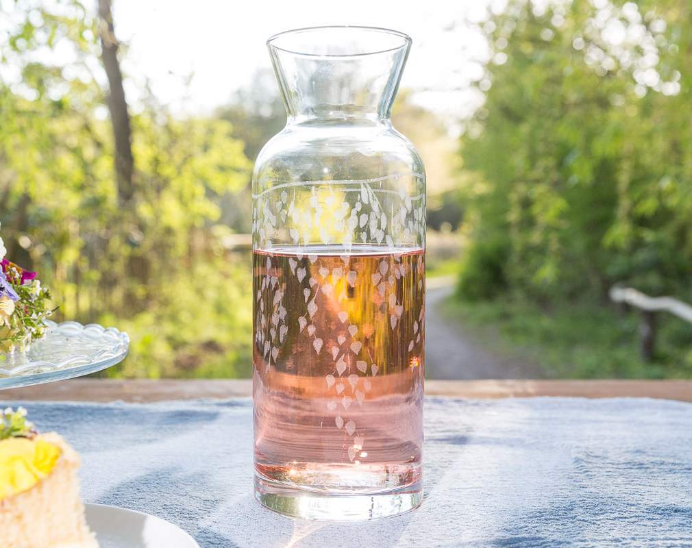 Clear glass carafe with floral design on a table outdoors
