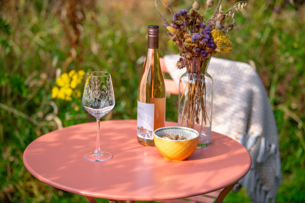 Table with wine bottle, glass, and bowl outdoors