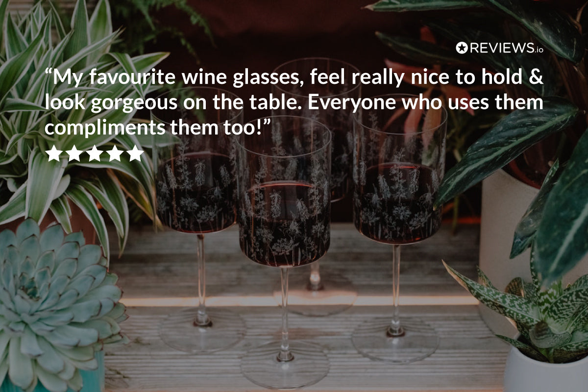 Wine glasses on a wooden surface with plants and a five-star review text overlay.