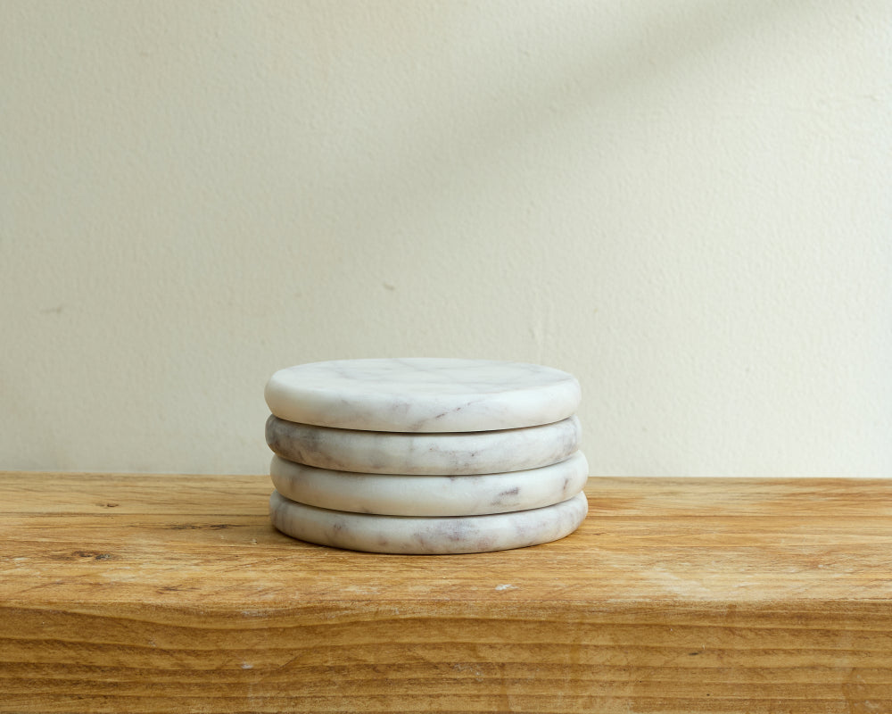 Stack of marble coasters on a wooden surface with a plain background