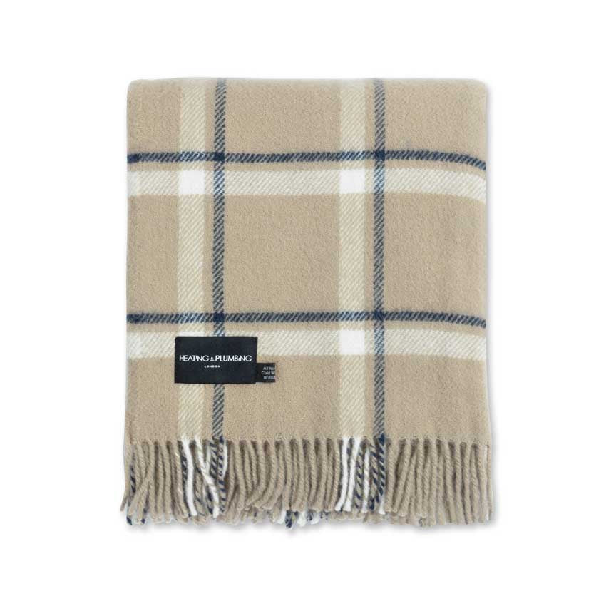 Beige and blue plaid blanket with a brand label on a white background
