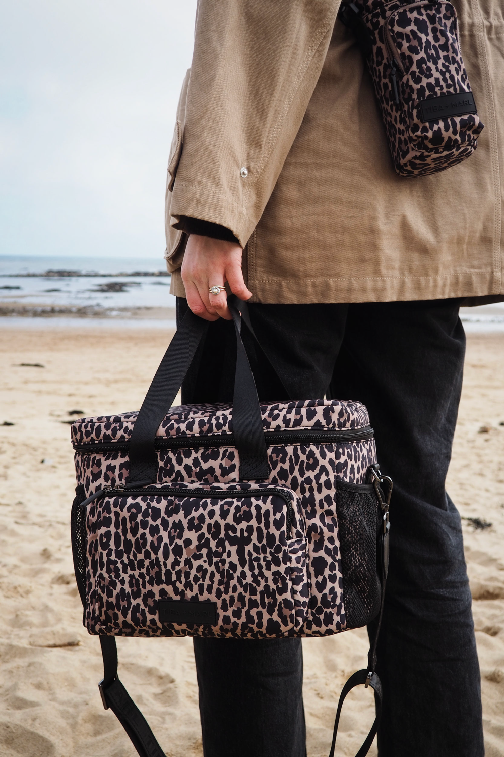 Person holding a leopard print coolbag on a beach