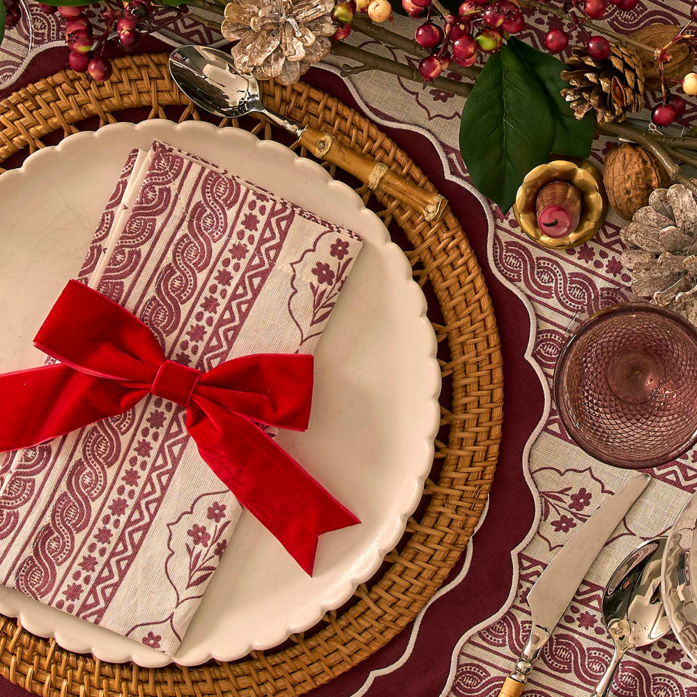Decorative table setting with a red ribbon, patterned napkin, and Christmas-themed decor.