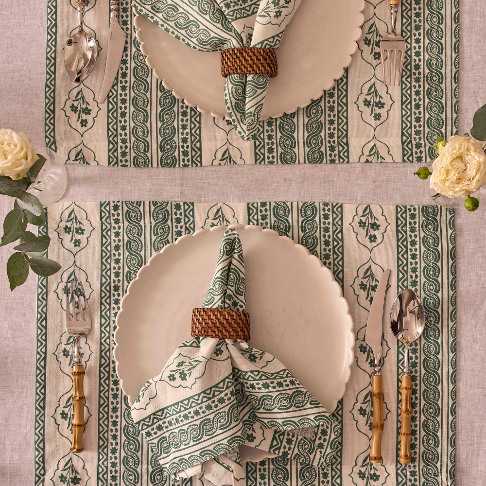 Decorative table setting with patterned placemats, plates, and cutlery on a matching tablecloth.