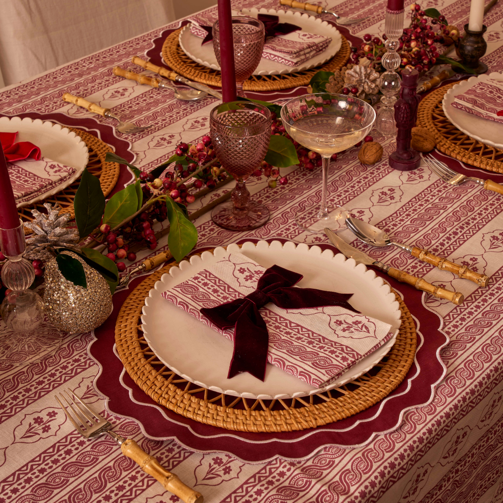 Elegant table setting with place mats, plates, and cutlery on a patterned tablecloth.