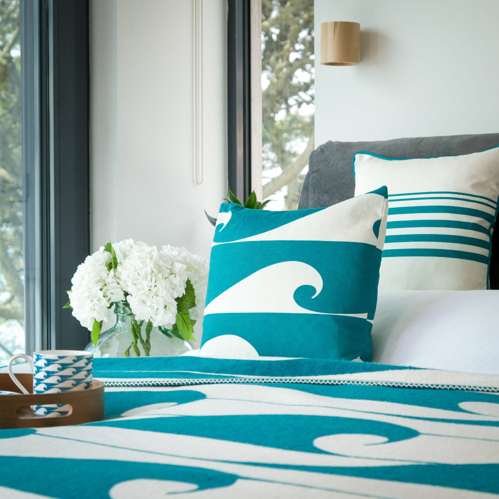 Bedroom with blue and white wave-patterned bedding and pillows.