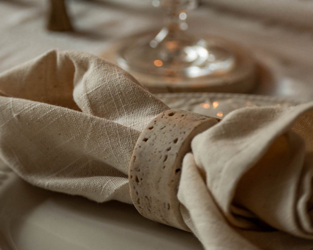 Close-up of a beige travertine napkin with a decorative ring on a blurred background