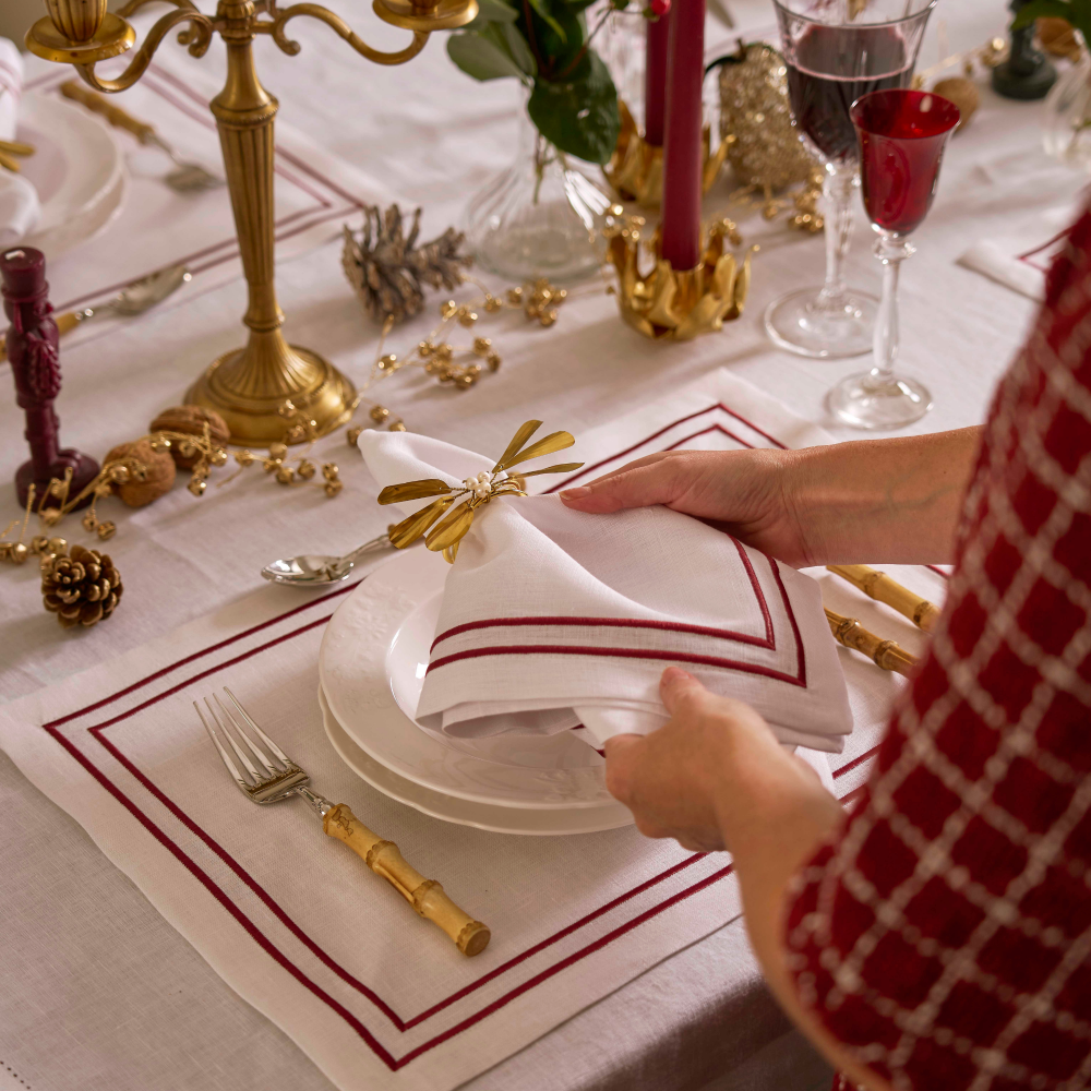 Person setting a festive table with red and gold accents