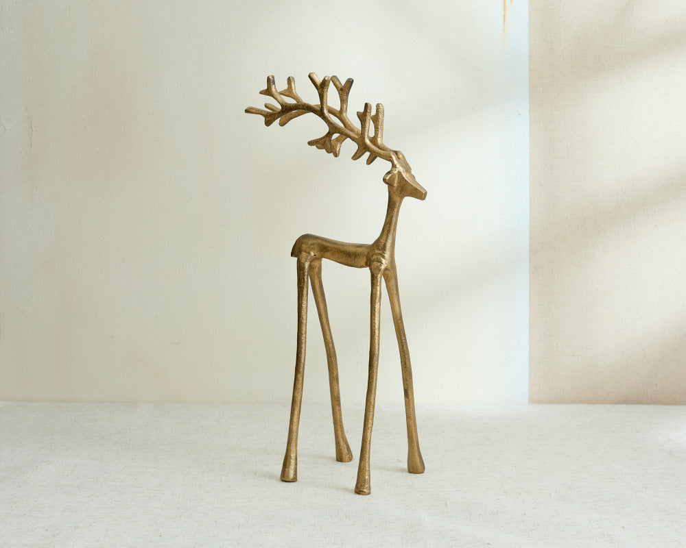 Gold deer figurine on a white surface with a neutral background