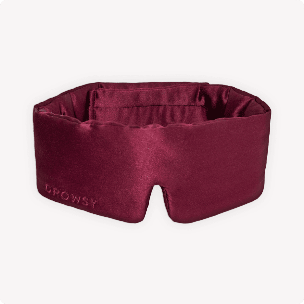 Maroon sleep mask with 'Drowsy' branding on a white background
