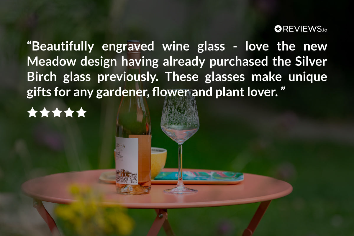 Wine bottle, wine glass, and small container on a table with a blurred outdoor background