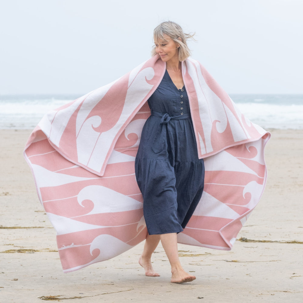Woman on a beach with a pink and white patterned towel draped over her shoulders