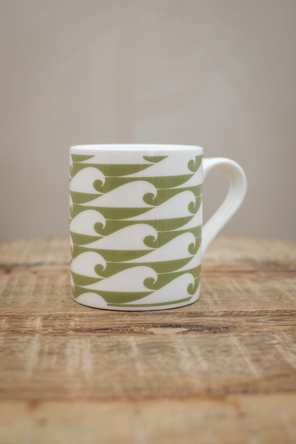 White Espresso mug with green wave pattern on a wooden surface
