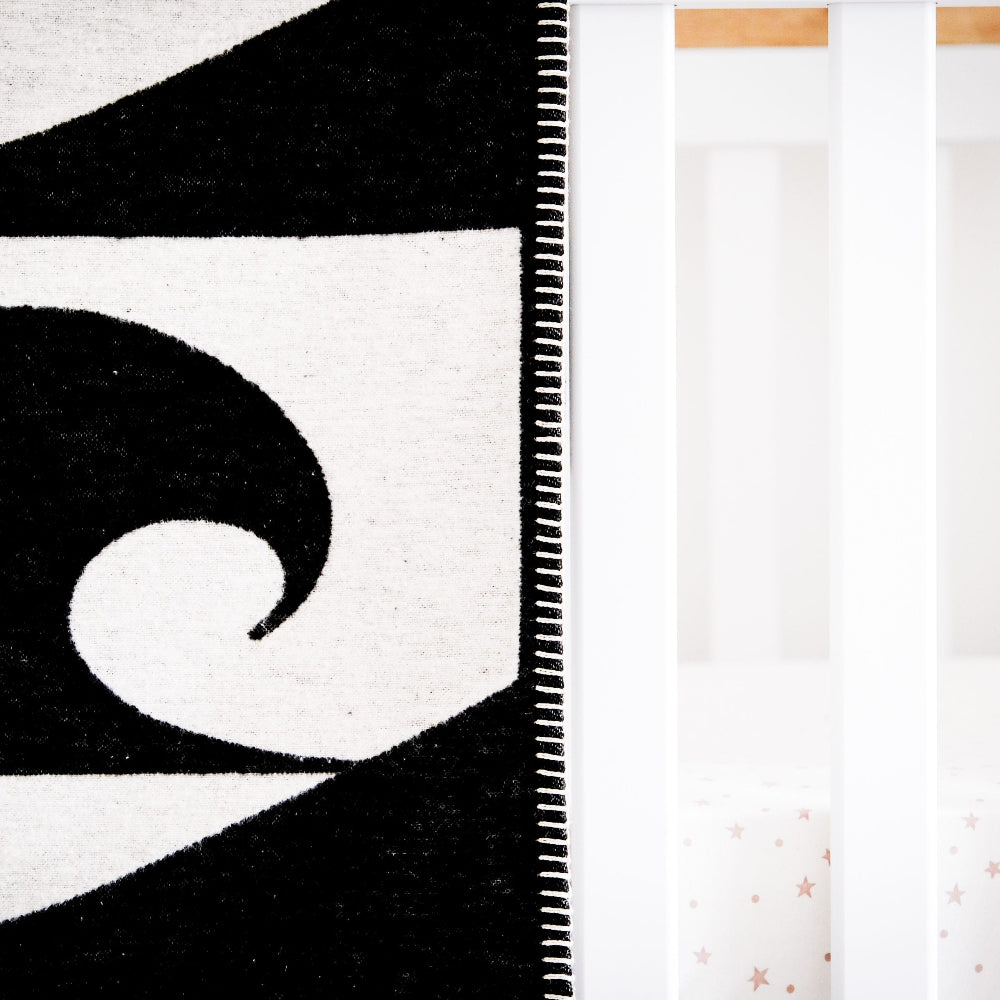 Close-up of a black and white patterned rug with geometric design on a wooden floor.