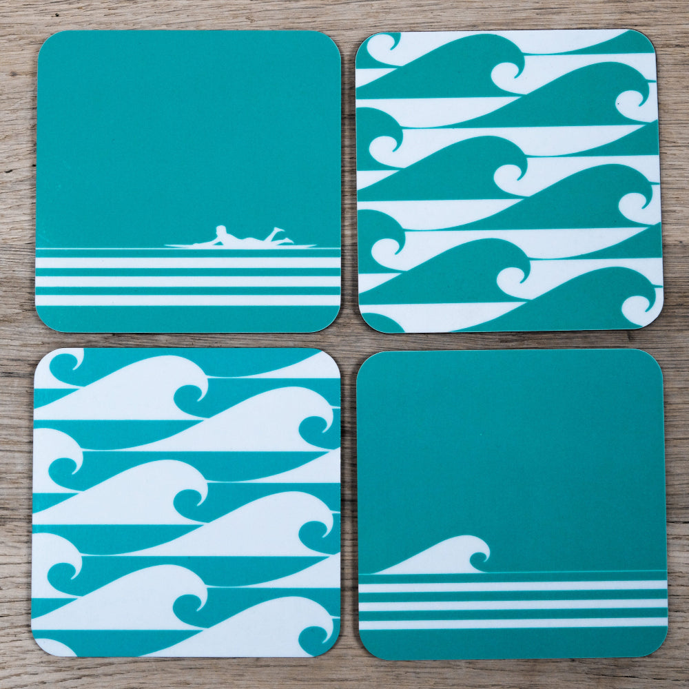 Four teal coasters with wave patterns on a wooden surface