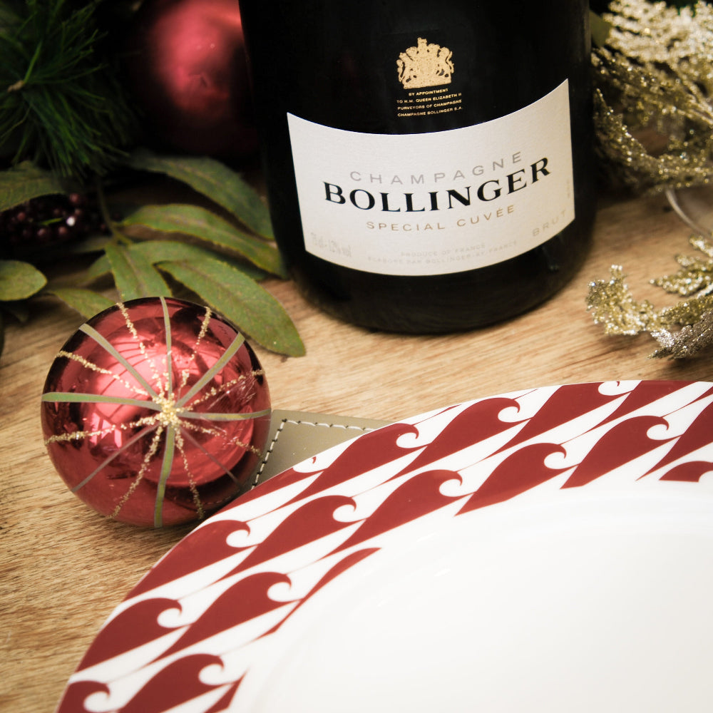 Bollinger champagne bottle with Christmas decorations and bone china plate on a wooden surface