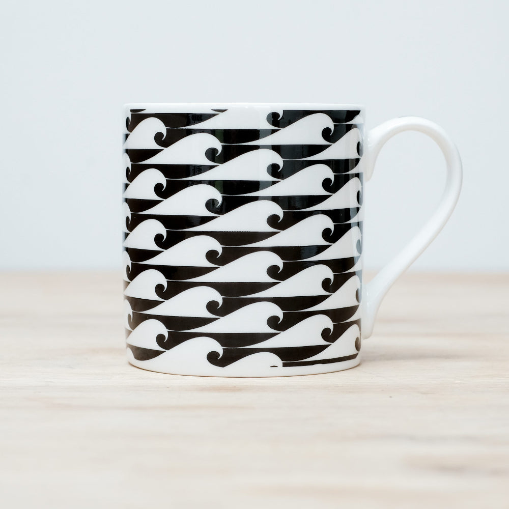 Mug with black and white wave pattern on a light wooden surface