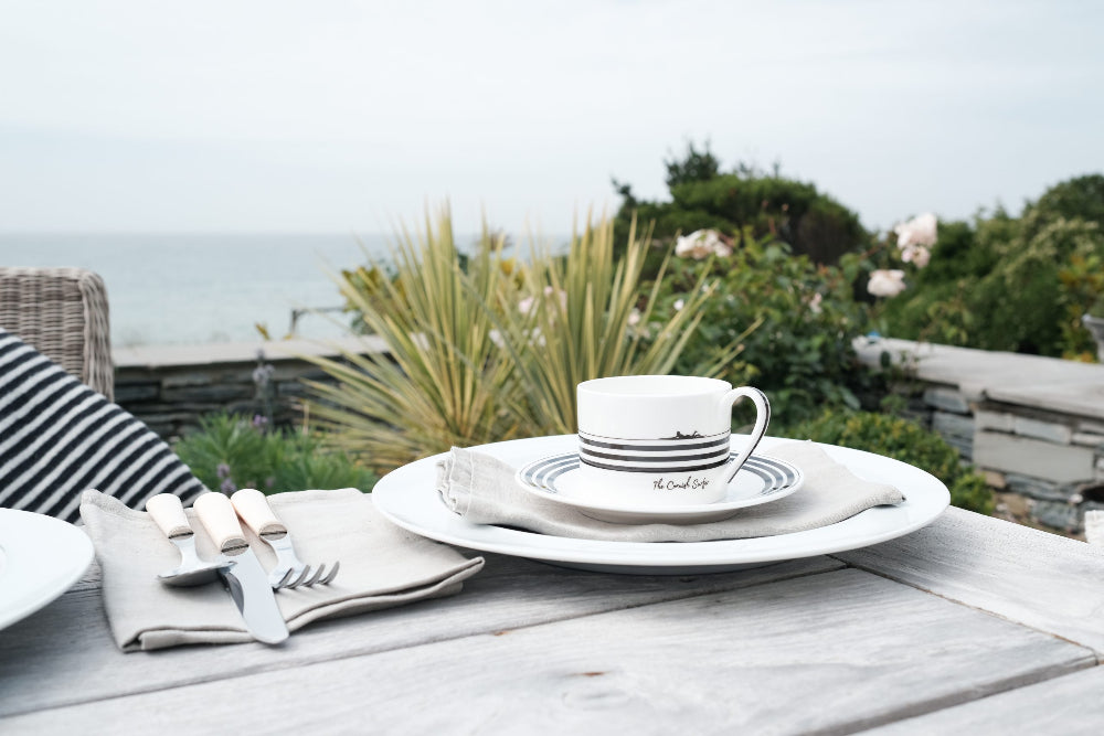 Café table setting with a cup and saucer on a wooden table outdoors.