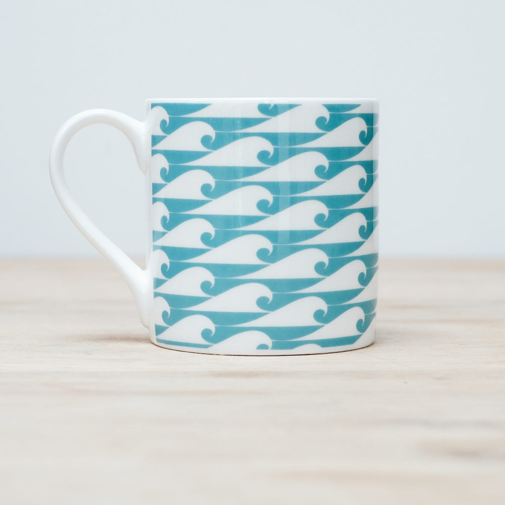 Mug with teal and white wave pattern on a light background