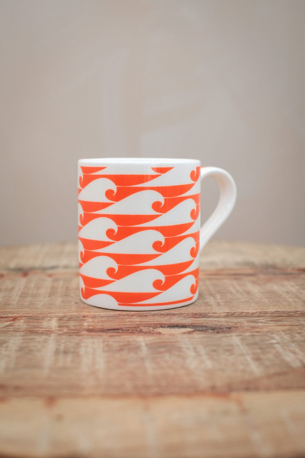 The Shorty Espresso Cup with wild pink salmon colour waves on a wooden table