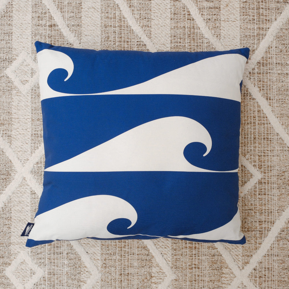 Decorative pillow with blue and white wave pattern on a textured beige background