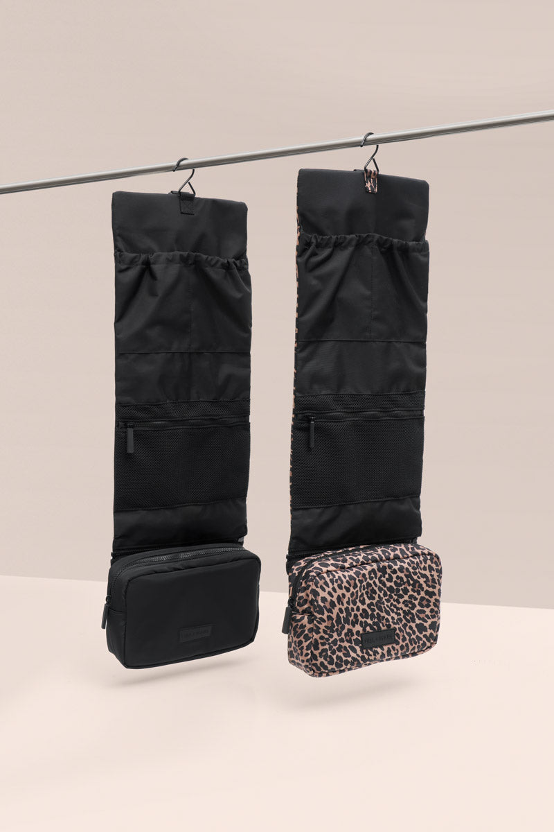 Black travel organizer with leopard print pouch on a beige background hanging on a line