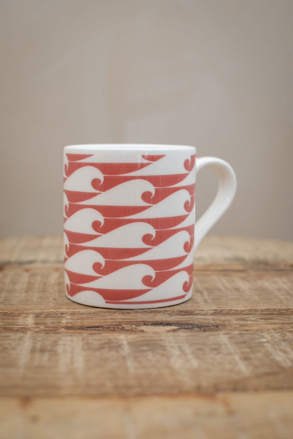White mug with red wave pattern on a wooden surface