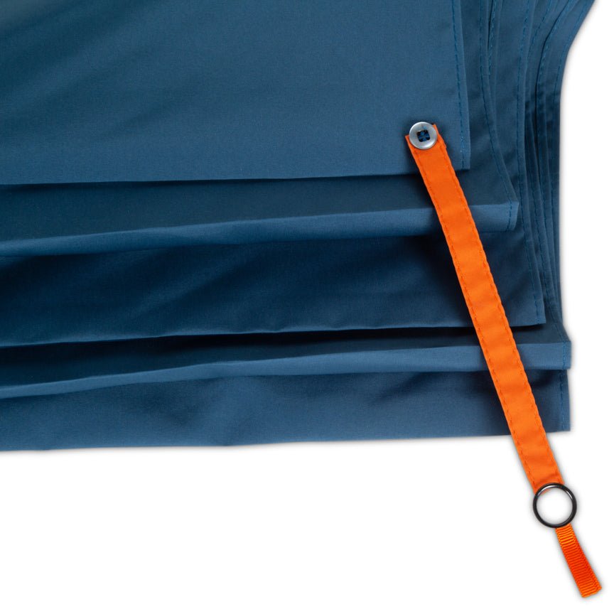 Close-up of a blue umbrella fabric with an orange strap and metal buckle on a white background