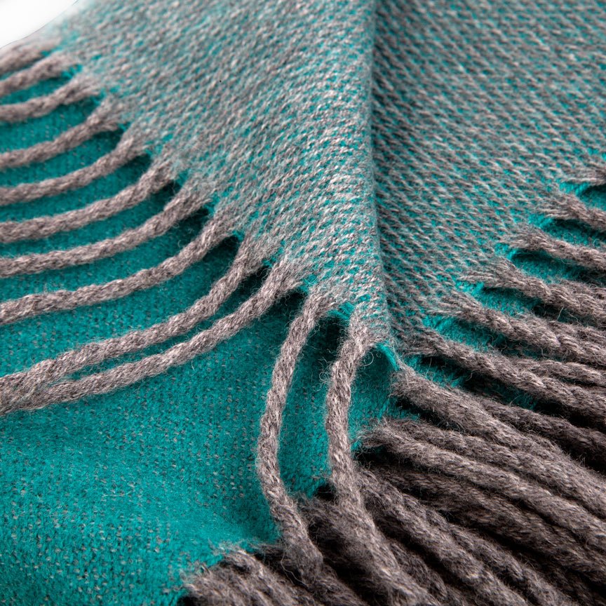 Close-up of a teal blanket with grey fringe
